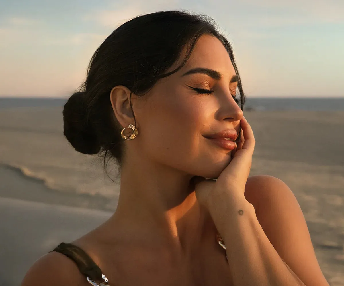 A woman by the sea resting her cheek on her hand
