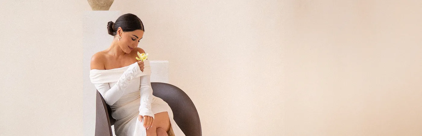A woman in white sitting on a chair in a soft pink room