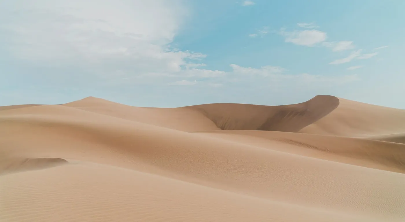 Soft sand dunes under a pale blue sky