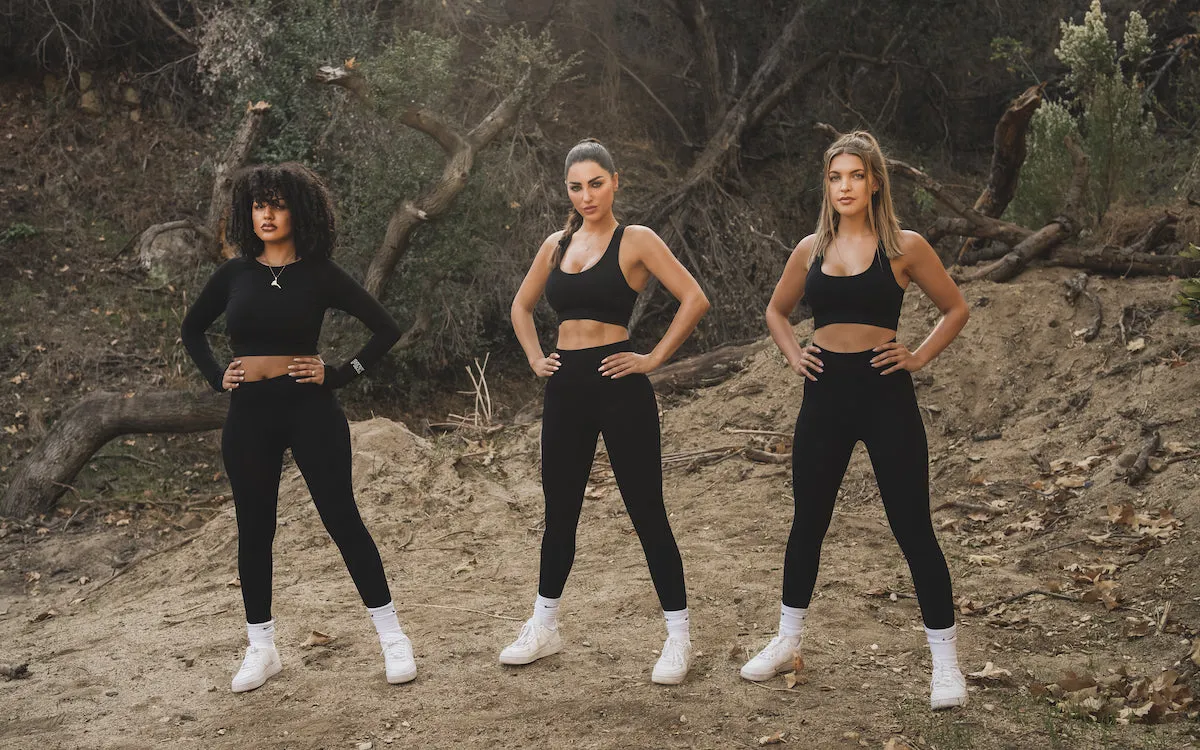 Three women in black training sets standing together outdoors